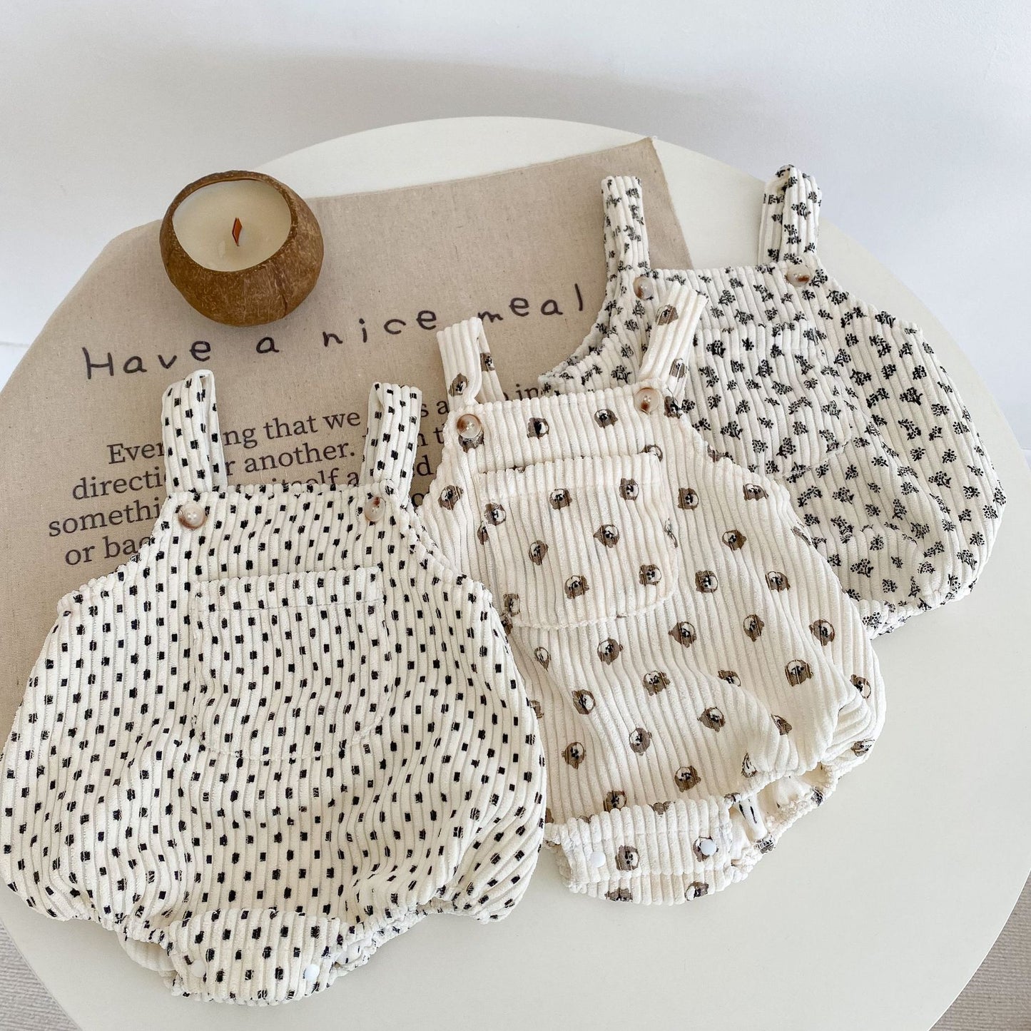 Two baby rompers with polka dot and floral patterns on a white surface.
