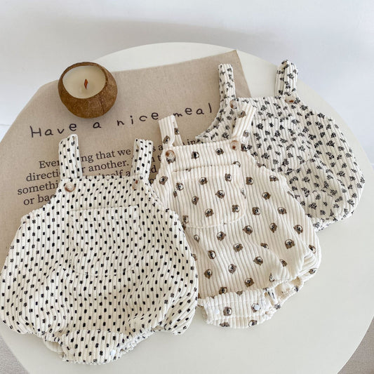 Two baby rompers with polka dot and floral patterns on a white surface.